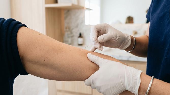 Dermatologista aplicando tratamento com agulha fina no braço de paciente